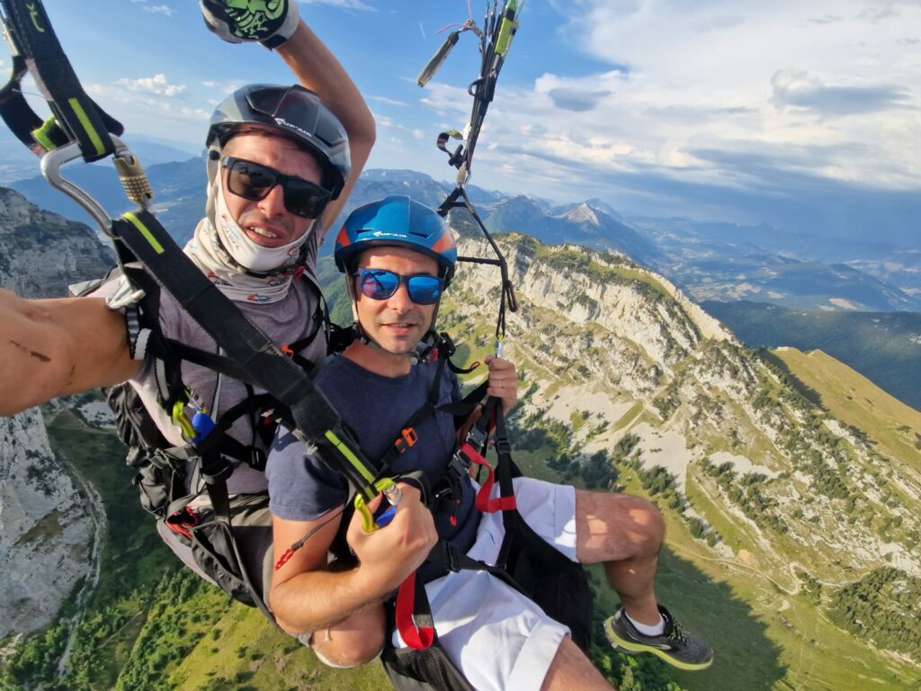Un homme qui vole en bapteme de parapente avec un moniteur de chez push up parapente au dessus des montagnes au col de la forclaz.
